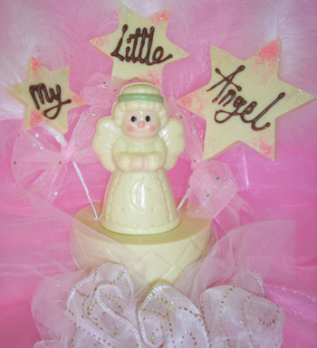 white chocolate angel on singe white chocolate tier, decorated with coloured chocolate and pink ribbon