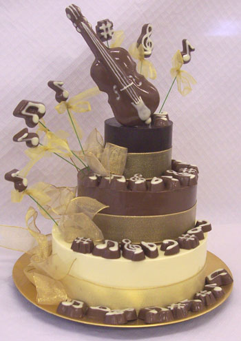 a picture of milk chocolate violin on three chocolate tiers, decorated with white chocolate and musical notes