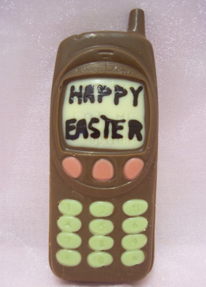 a picture of a milk chocolate mobile phone decorated with white and coloured chocolate. Display screen says 'happy easter'