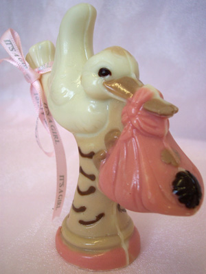 a picture of a white chocolate stork carring a baby decorated with milk, dark and coloured chocolate