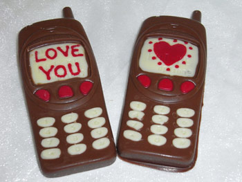 Two milk chocolate valentine mobile phones decorated with White and coloured chocolate. One display shows a Love You message, the other a heart