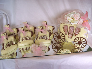 a picture of a white chocolate wedding carriage and horses, decorated with pink ribbon and butterfly