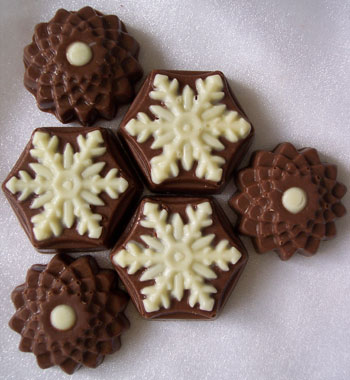 a picture of six chocolate snowflates, decorated with white and milk chocolate.